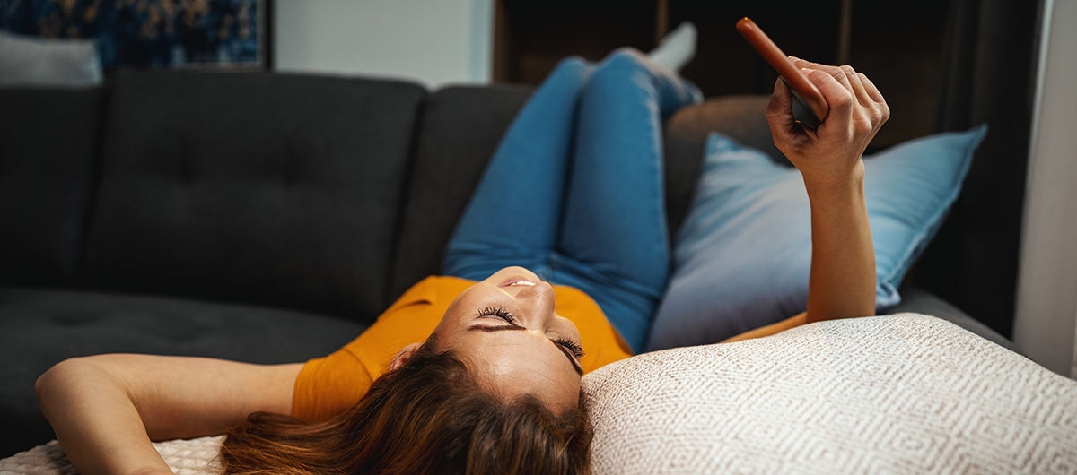Wondering How to Get Higher on Less Weed? 4 Relaxed woman chilling at home on her sofa and mobile phone. Buy weed online in Ajax cannabis dispensary weed delivery.