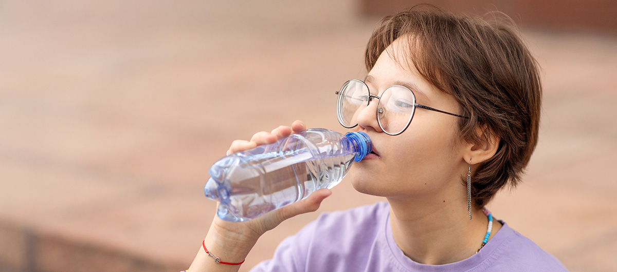 woman drinking water from a bottle. buy weed near me.