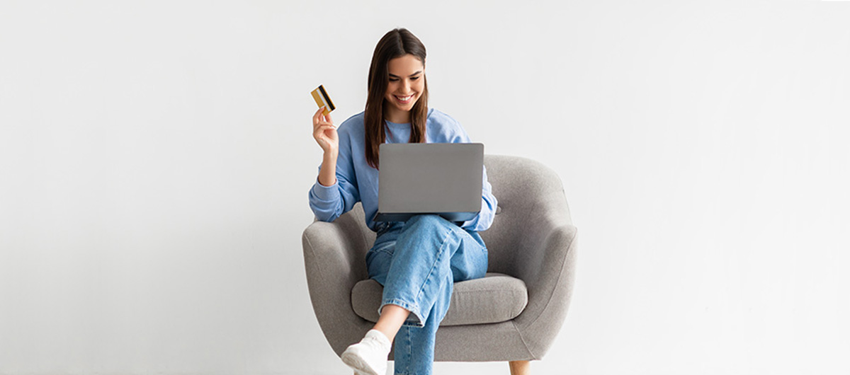 happy woman sitting on an arm chair shopping online