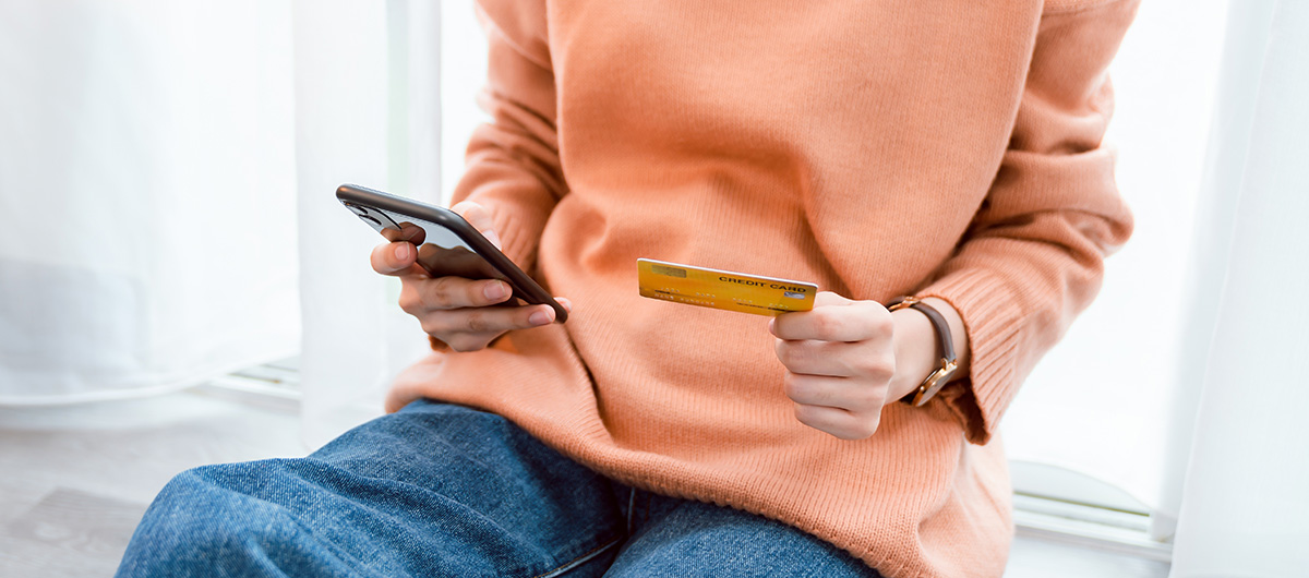 woman holding credit card and smartphone shopping online